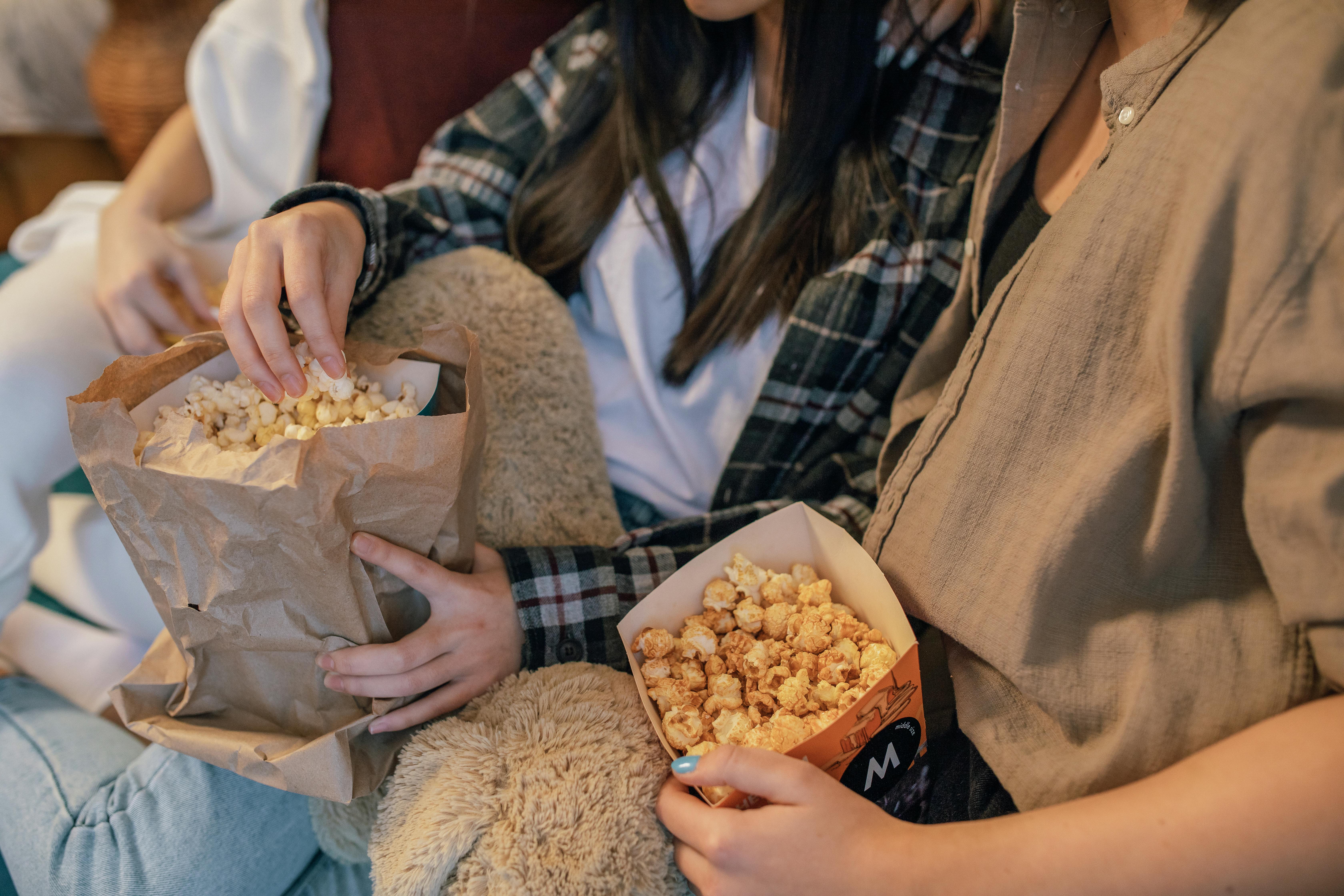 Teenager sitzen zusammen bei einer Film-Party mit Popcorn und Kinoatmosphäre